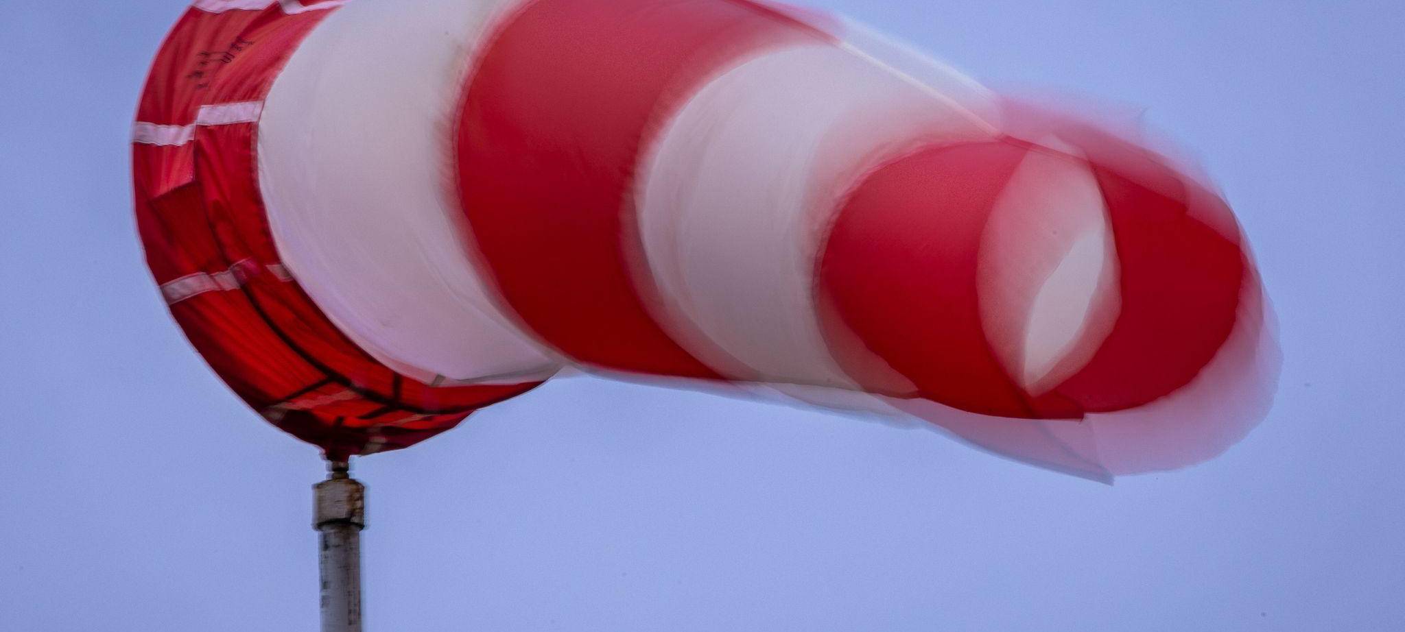 Windsack weht bei Regen und kräftigem Wind am Mast
