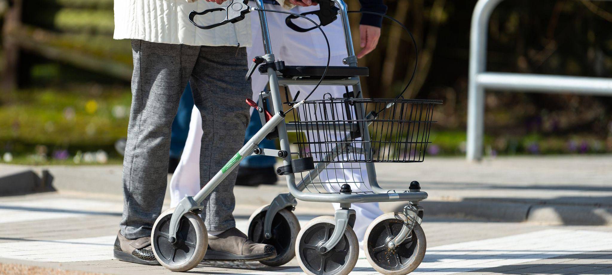 Physiotherapeutin erklärt einer Seniorin den Umgang mit Rollator