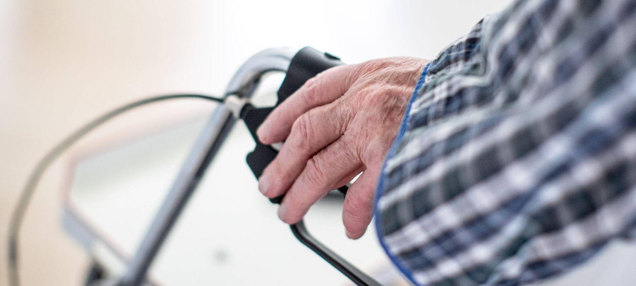 Mann stützt sich auf seinen Rollator