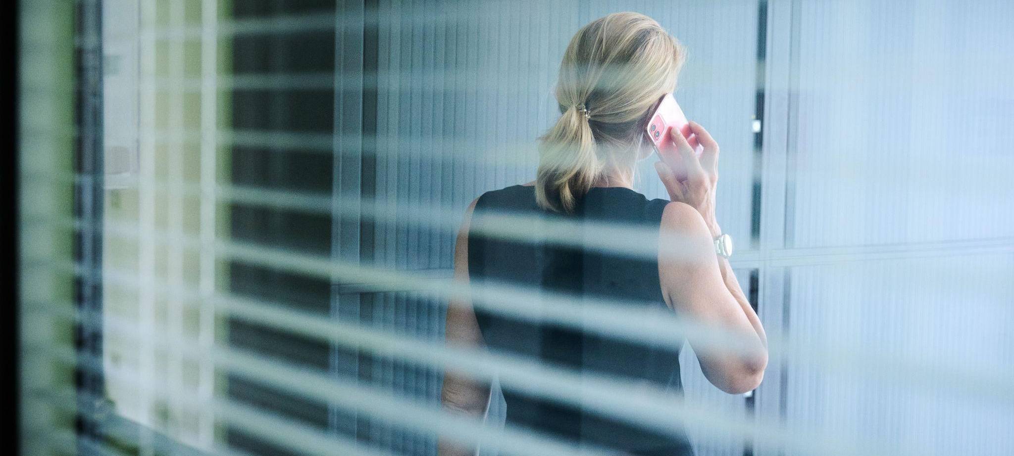 Frau steht telefonierend in einem Büro