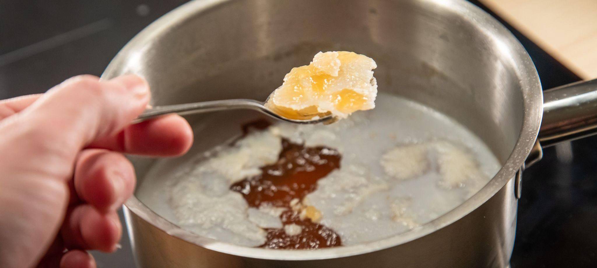 Fett wird mit einem Löffel von einer Brühe geschöpft