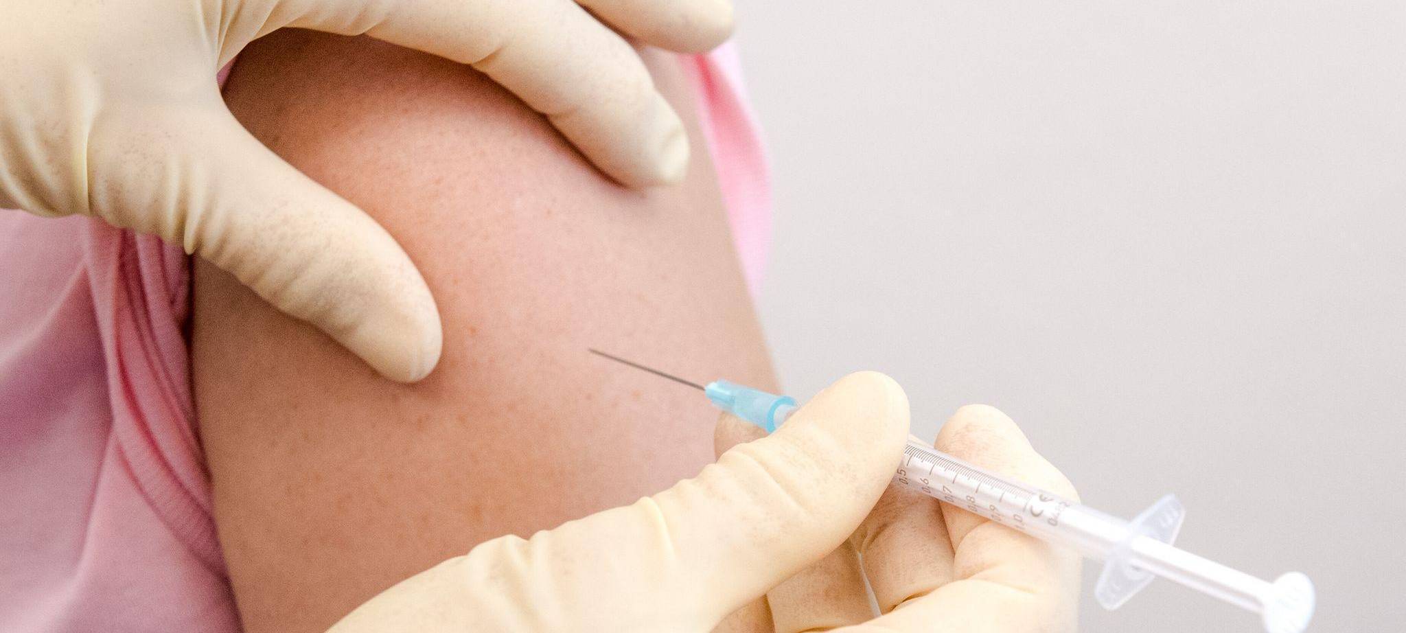 Eine Frau wird in den Oberarm geimpft