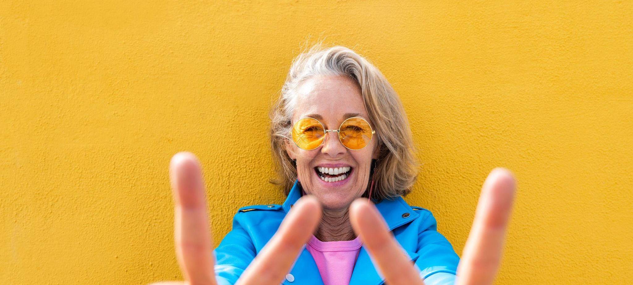 Frau lächelt in die Kamera und zeigt Peace-Zeichen