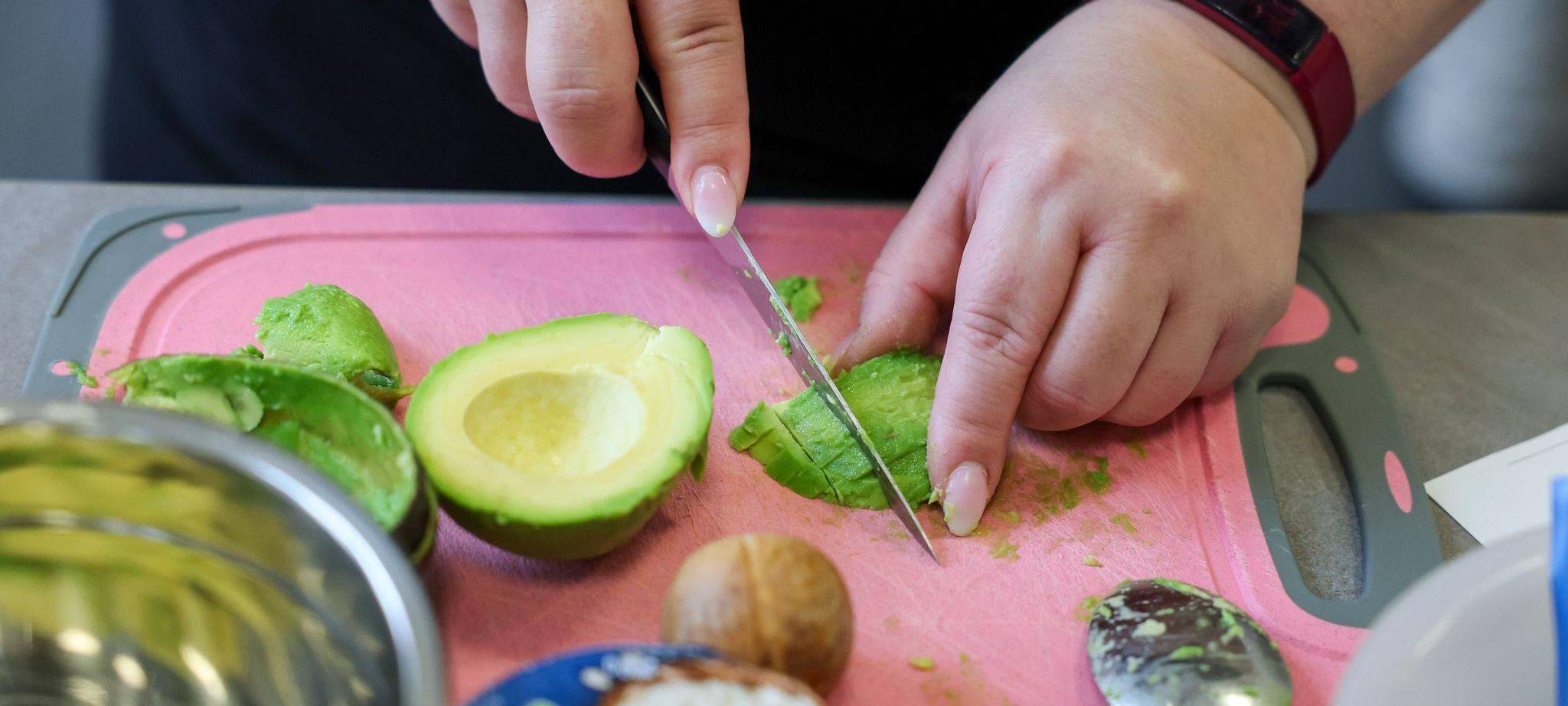 Eine übergewichtige Frau schneidet Avocado