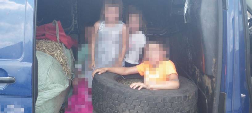 Kinder zwischen Stroh und Reifen auf der Ladefläche